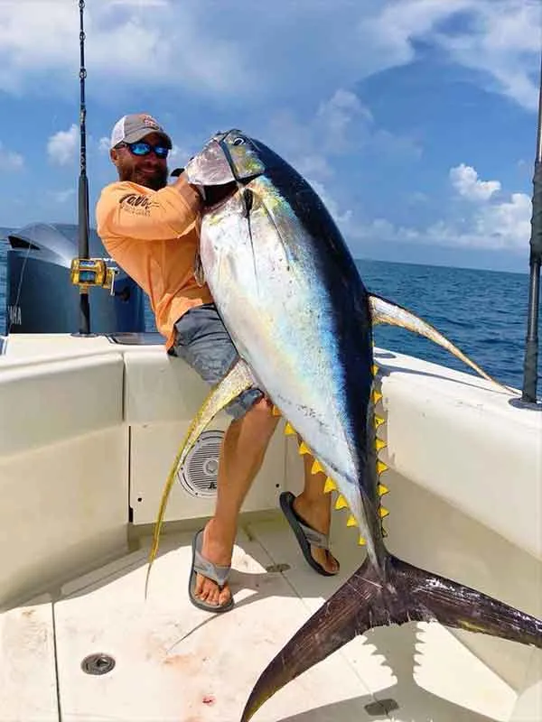 Man holds giant yellowfin tuna catch during a Key West Deep Sea Fishing Charter.